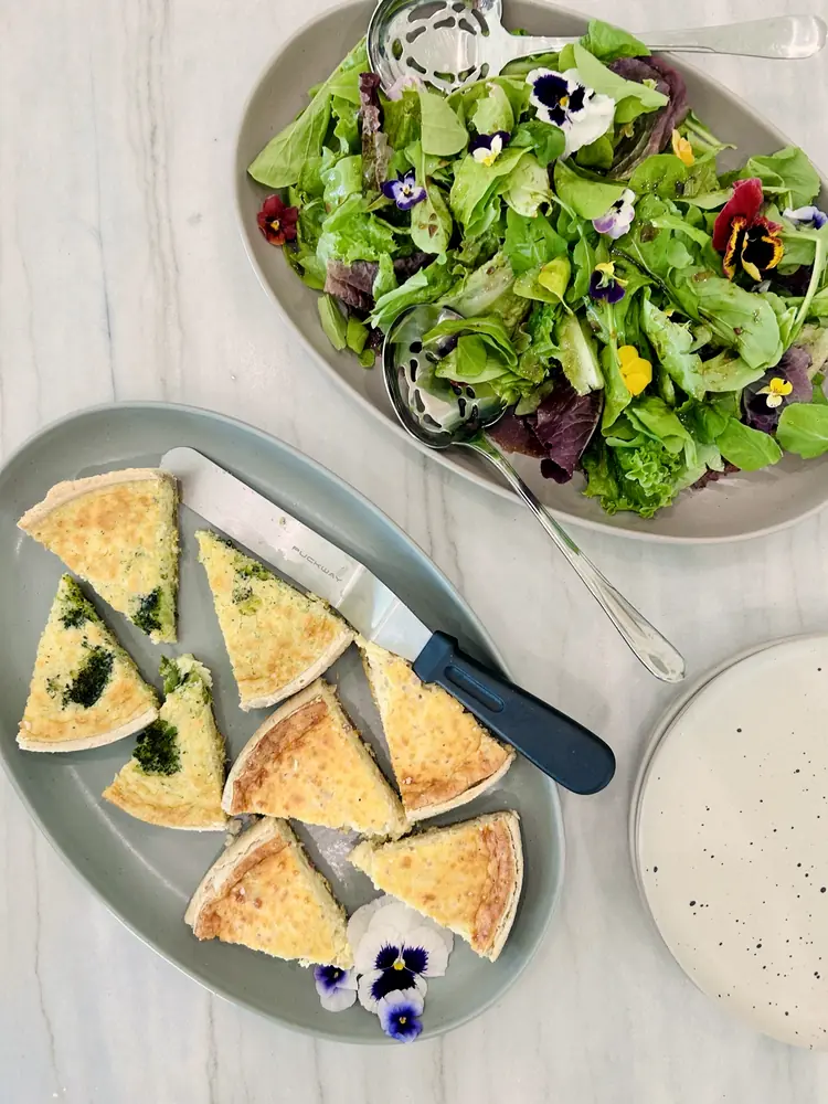 An overhead spread of fresh seasonal salad and savory tarts at a Becoming Beautifully gathering.